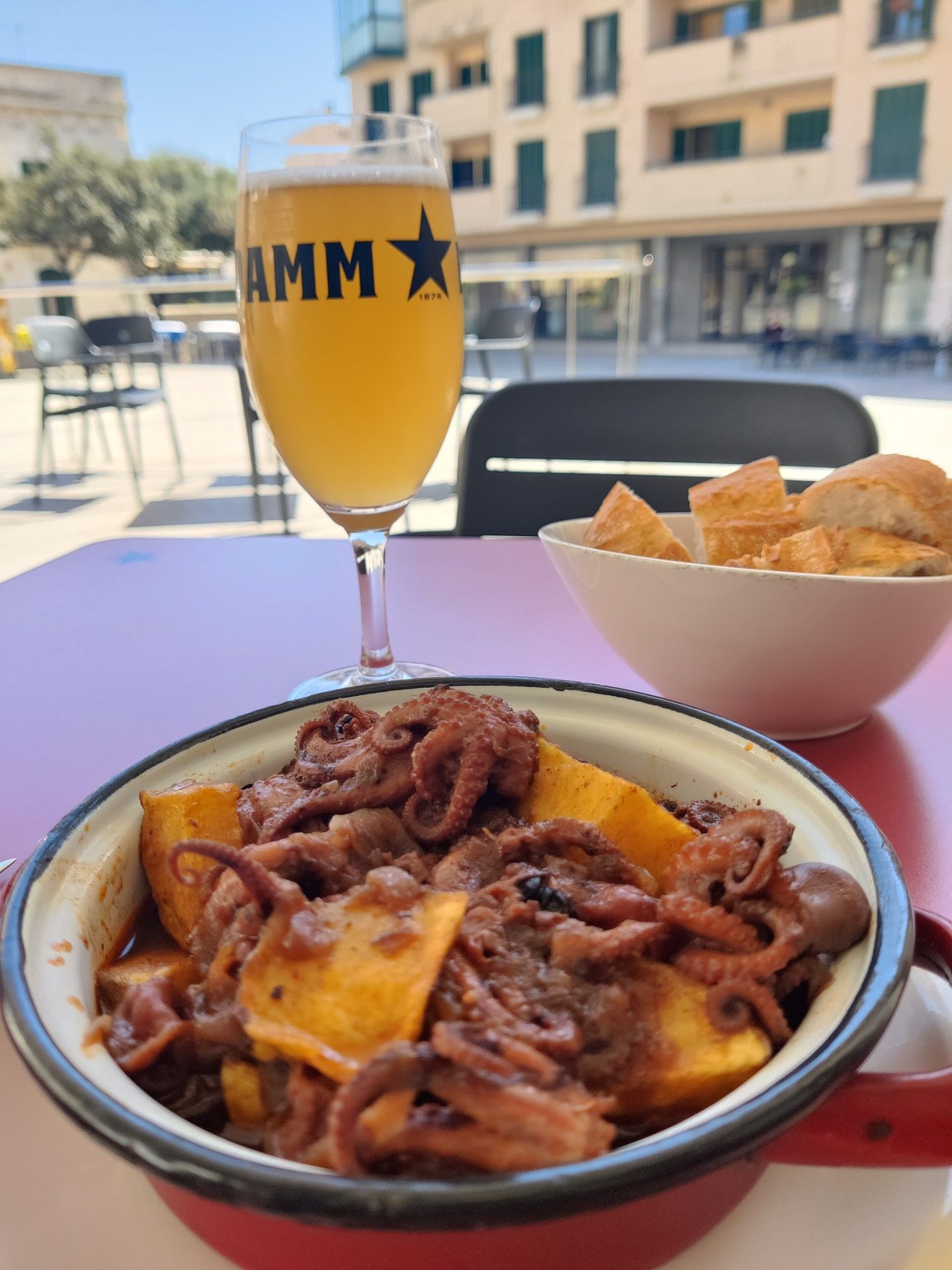 Popets encebats a la terrassa dels Salistes amb cervesa Damm i la plaça d'Olesa al fons